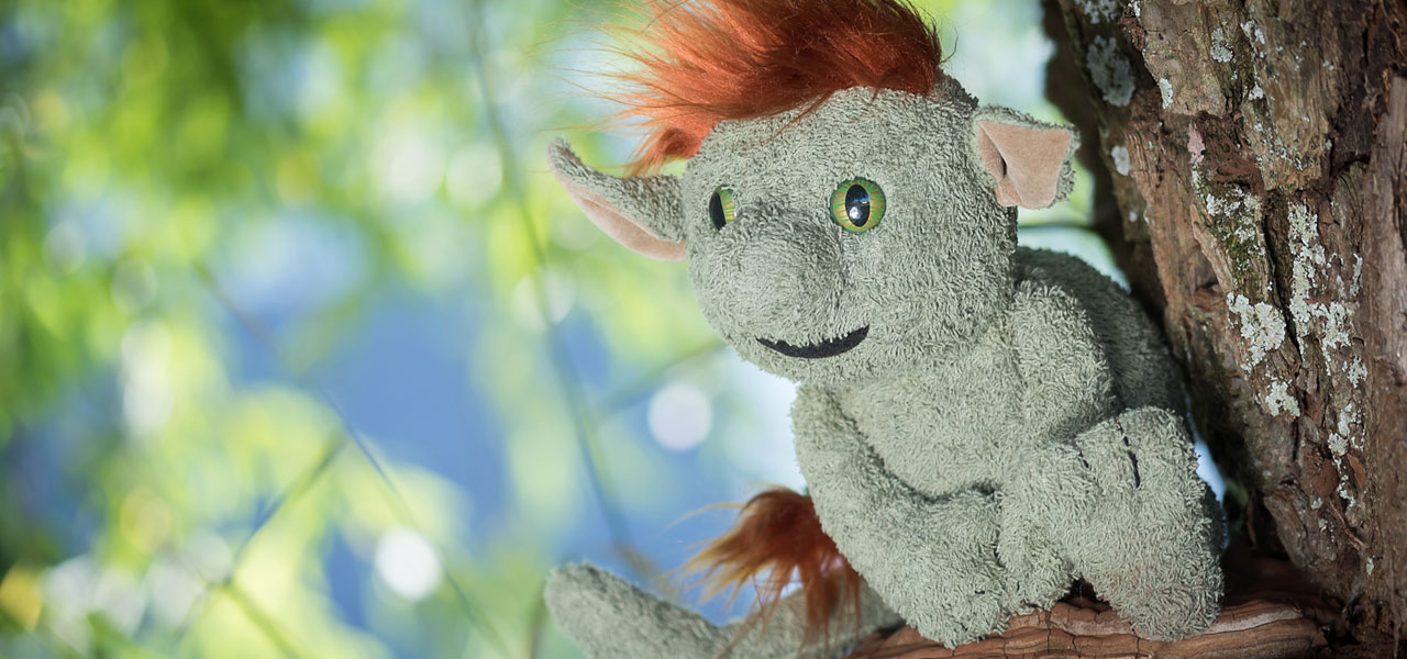 Grüner Kobold mit braunen Haaren sitzt im Baum